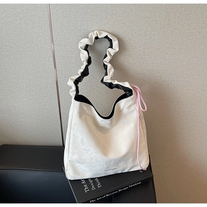 Gros plan sur un sac cabas blanc plissé avec lettrage mode et détails de cordon rose