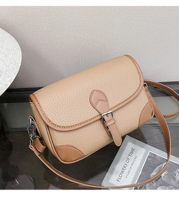 Detailed close-up of beige and brown leather small square bag with metal buckle and strap