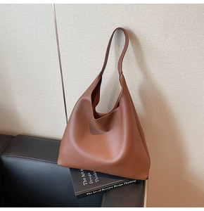Dettaglio macro della borsa hobo in pelle martellata marrone su un divano nero