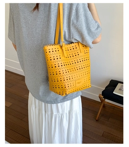 Detail of laser-cut geometric holes and scalloped edges on a bright yellow tote bag