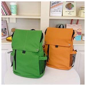 Détail de sacs à dos en nylon vert et orange avec fermeture à pression sur un bureau