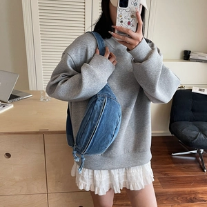 Blue denim crescent chest bag worn across the body with adjustable strap in casual style