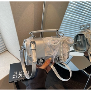 Détail du sac argenté avec nœud en dentelle de perles et boucles décoratives