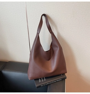 Vista dettagliata della borsa tote in pelle marrone scuro con trama a grana su sfondo elegante