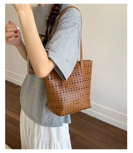 Close-up of brown PU tote bag with laser-cut geometric hollow patterns and wavy edges