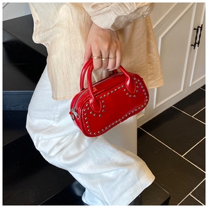Close-up of a glossy red patent leather handbag with silver stud details and handles