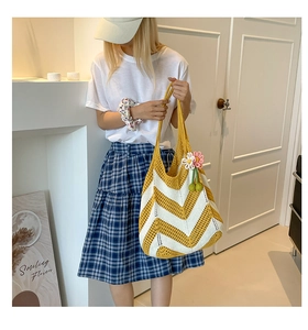 Close-up of woven straw tote bag with yellow stripes and pink flower charm detail