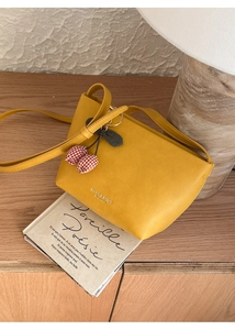 Detail of yellow tote bag with tulip charm on a rustic wooden background with a book