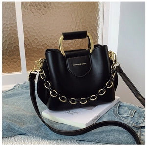 Detail of black crossbody bucket bag with golden chain handle and fashion engraving