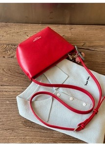 Detail of red leather crossbody bag with logo, adjustable strap and bear pendant