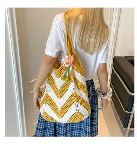 Detailed view of woven shoulder bag with floral pendant on a female model