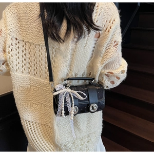 Détail du sac bandoulière cylindrique noir avec nœud en perles et charme en dentelle
