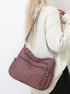 Quilted heart nylon crossbody bag in dusty rose featuring multi-zipper compartments