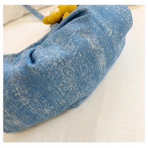 Détail d'un sac à main en denim délavé bleu clair avec un joli charme de fleur jaune