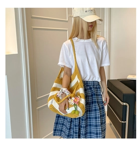 Detailed close-up of yellow and white striped woven tote with pink floral charm
