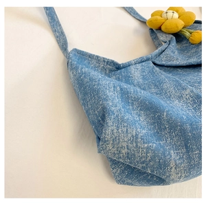 Détail du sac en jean bleu avec une breloque tournesol jaune et texture de tissu doux