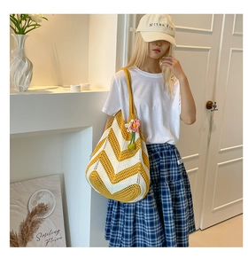 Detail of hand-woven tote bag with yellow wave pattern and pink floral charm
