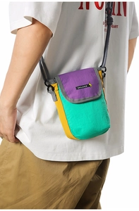 Detail of multi-color crossbody mini bag featuring purple flap and mint green front panel