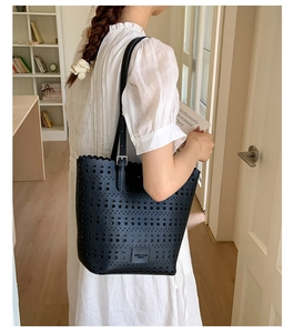 Close-up of black hollow-out leather tote bag with laser-cut geometric patterns and strap
