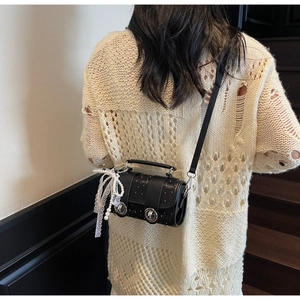 Vue détaillée du sac cylindre noir avec clous argentés et nœud en dentelle sur mannequin