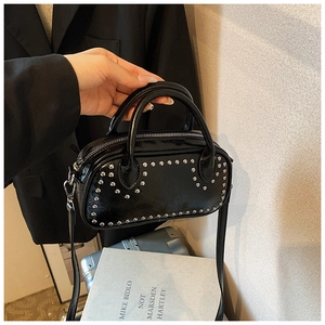 Detail view of black faux leather handbag with silver studs and top handle strap