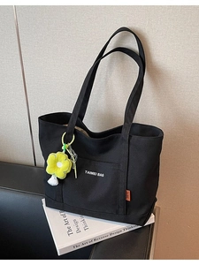 Borsa tote in tela nera con spalline e un ciondolo decorativo a forma di fiore giallo