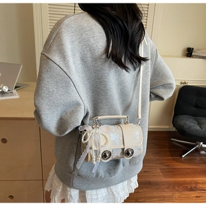 Détail du sac Boston crème avec nœuds en dentelle et breloque perle sur bandoulière