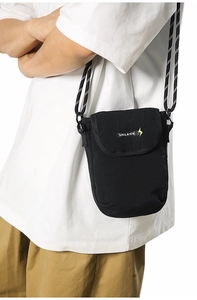 Detailed view of a black nylon mini crossbody bag featuring a branded flap and woven cord strap