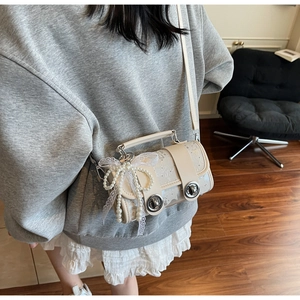 Vue détaillée d'un sac crème avec des perles et un nœud en dentelle sur un sol en bois