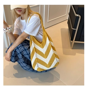 Close-up of a hand-woven shoulder bag featuring yellow and white wavy patterns and textures
