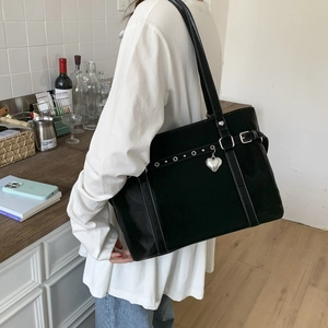 Detail of black tote bag with silver heart charm and metal eyelets on model