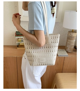 Detail of white laser-cut tote bag with scalloped edges and minimalist leather brand label