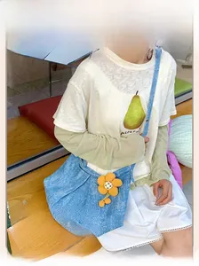 Détail du sac bandoulière en denim bleu avec design plissé et breloque fleur jaune