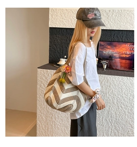 Detail of hand-woven chevron shoulder bag with floral pendant and texture