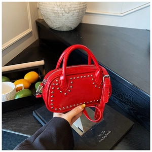 Detail of red glossy mini handbag featuring silver studs and detachable shoulder strap