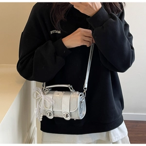 Détail du mini sac cylindrique argenté avec paillettes et breloque en dentelle