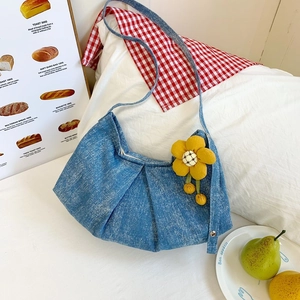 Détail du sac hobo en jean bleu clair avec texture plissée et breloque fleur jaune
