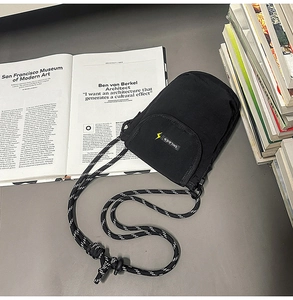 Close-up of minimalist black crossbody phone bag with yellow lightning logo and rope strap
