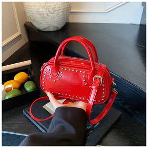 Detail of red glossy PU leather handbag featuring silver studs heart pattern decoration