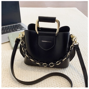 Detail of black PU leather bucket bag with gold metal handle and fashion text logo