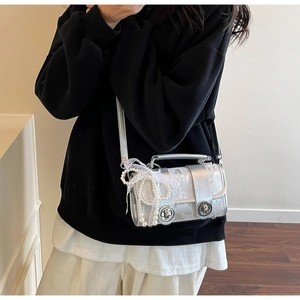 Détails du mini sac argenté avec nœud en dentelle blanche et chaîne de perles