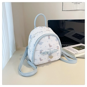 Détail du mini sac à dos blanc et bleu avec motif lapin et pendentif cœur en métal