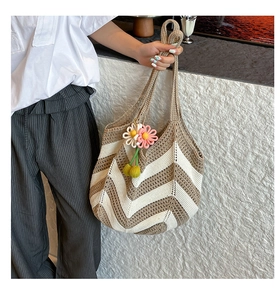Detailed view of beige woven handbag with wavy patterns and a colorful floral pendant