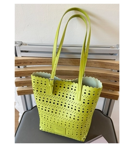 Detail of laser-cut geometric hollow patterns on a bright green faux leather tote bag