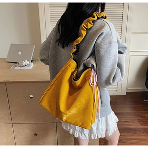 Détail d'un sac cabas jaune vif avec bretelles à volants et cordons de serrage latéraux