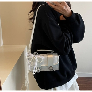 Détail d'un mini sac argenté avec nœud en dentelle et perles de décoration