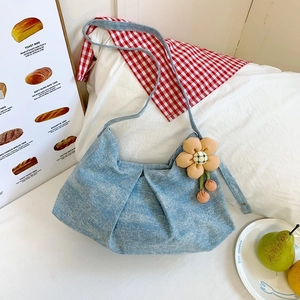 Détail du sac en jean bleu clair avec texture plissée et breloque fleurie en tissu