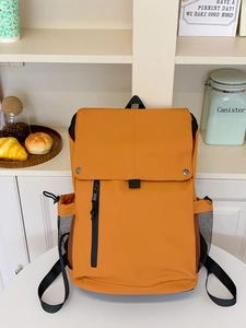 Sac à dos en nylon orange avec grand rabat et boucles en métal sur une table blanche