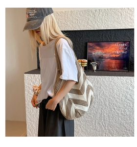 Detail of a large woven tote bag with brown and white chevron knit patterns on a shoulder strap