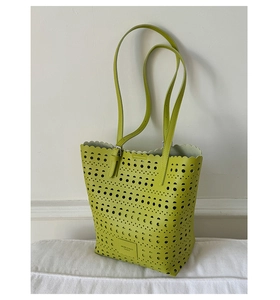 Close-up of laser-cut hollow patterns and logo patch on the green tote bag